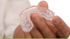 Hand holding clear dental mouthguard